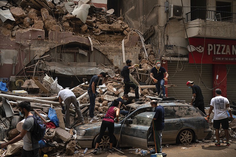 People remove debris from a house damaged by Tuesday's explosion in the seaport of Beirut, Lebanon, Friday, Aug. 7, 2020.