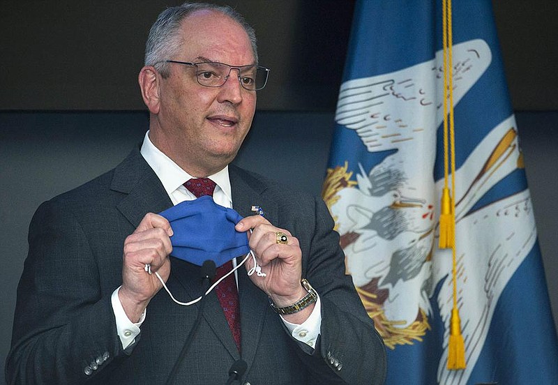 Louisiana Gov. John Bel Edwards holds up his mask during a news conference in Baton Rouge in late July.
(AP/The Advocate/Travis Spradling)