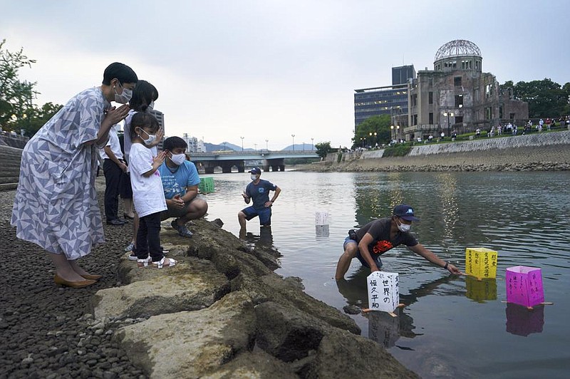 People pray as paper lanterns float Thursday along the Motoyasu River in front of the Atomic Bomb Dome marking the anniversary of the World War II bombing in Hiroshima, Japan.
(AP/Eugene Hoshiko)