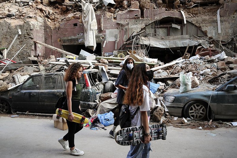 Women walk past destroyed vehicles Friday near the scene of Tuesday’s explosion in the Beirut seaport. More photos at arkansasonline.com/88beirut/
(AP/Thibault Camus)