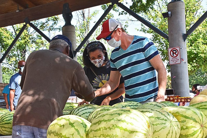 William Graves (left), an employee of Carpenter’s Produce, helps Kelly and James Fitzgerald of North Little Rock pick out a watermelon during the farmers market Saturday, Aug. 8, 2020, at the River Market in Little Rock.(Arkansas Democrat-Gazette/Staci Vandagriff)