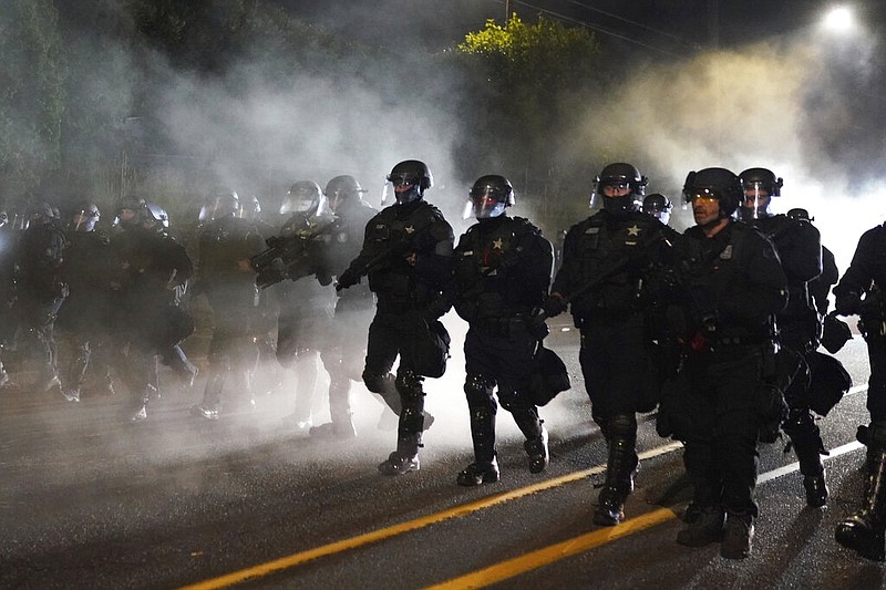 Portland police officers walk through the Laurelhurst neighborhood after dispersing protesters from Multnomah County Sheriff's Office early in the morning on Saturday, Aug. 8, 2020 in Portland, Ore. 