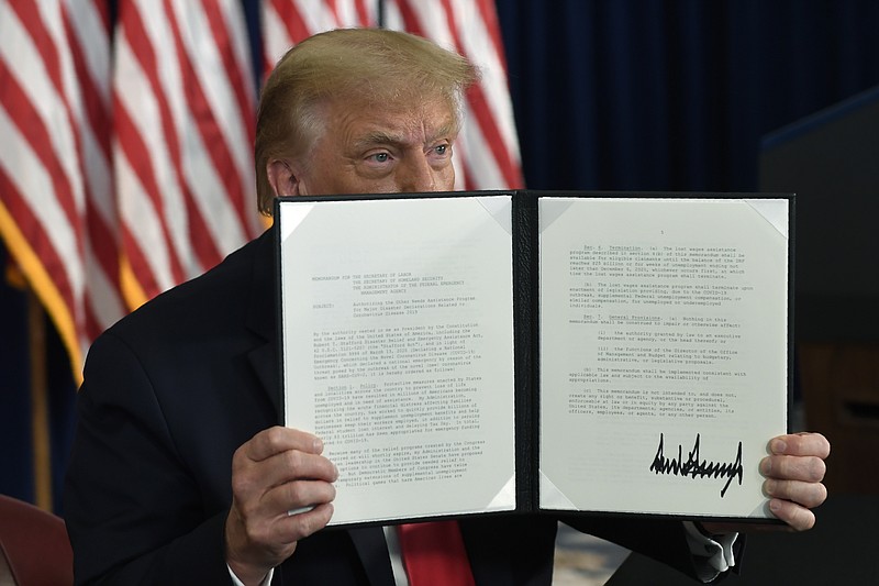 President Donald Trump signs an executive order during a news conference at the Trump National Golf Club in Bedminster, N.J., Saturday, Aug. 8, 2020. 