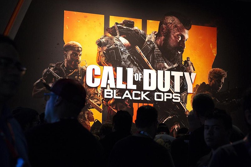 Attendees stand next to signage for Activision Blizzard’s Call Of Duty: Black Ops 4 video game during the E3 Electronic Entertain- ment Expo in Los Angeles, California, in 2018. (Bloomberg/Troy Harvey) 
