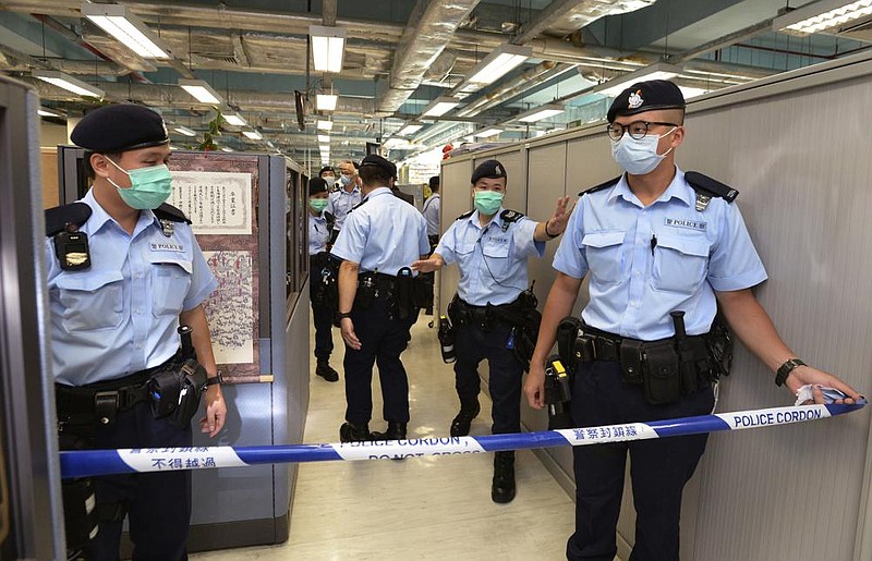 Police officers cordon off part of the Apple Daily newspaper headquarters Monday after founder Jimmy Lai was arrested at his home in Hong Kong. (AP/Apple Daily) 