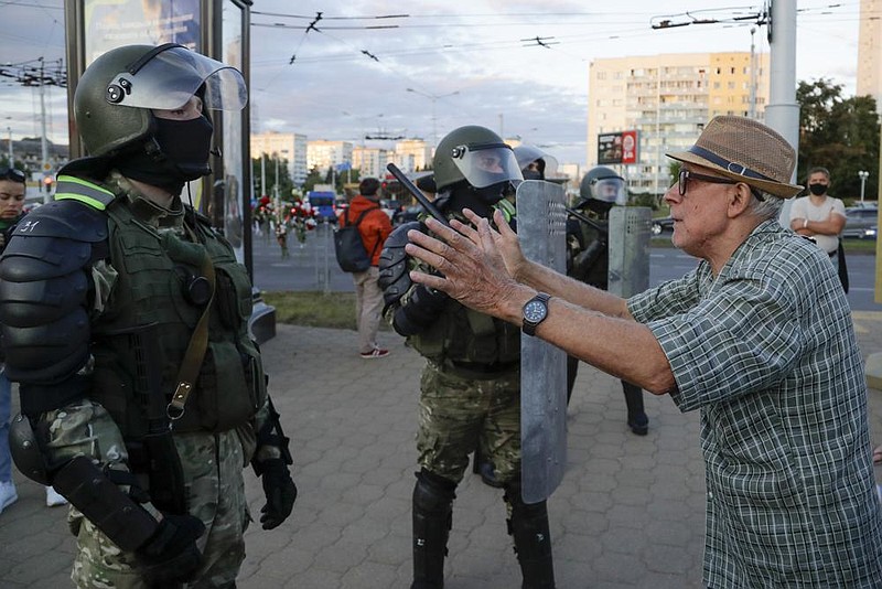 A elderly man talks with riot police officers Tuesday in Minsk, Be- larus. More photos at arkansasonline.com/812belarus/ (AP/Sergei Grits) 
