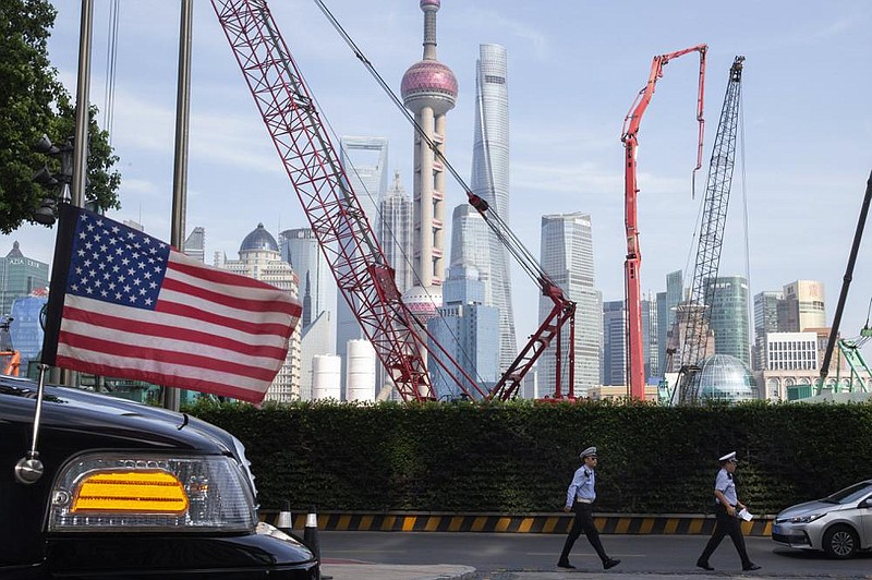 Chinese traffic police officers walk by a U.S. flag on an embassy car on July 30 outside a hotel in Shanghai where officials from China and the United States met for talks aimed at ending a tariff war.
(AP)