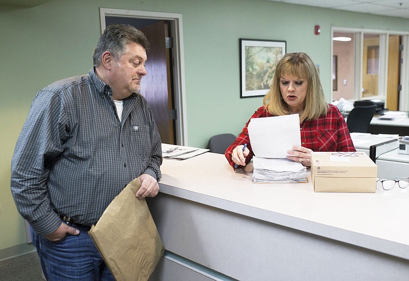 Jason Steele (left) gives Springdale City Clerk Denise Pearce a stack of petitions at Springdale City Hall in this March 6, 2020, file photo. The petitions called to have Bethel Heights annexed into Springdale, a proposal that was ultimately successful. (NWA Democrat-Gazette/Charlie Kaijo)