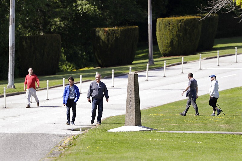 People walk at the border between the United States (foreground) and Canada at Peace Arch park in Blaine, Wash., in this May 17, 2020, file photo.