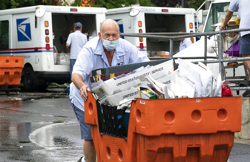 Letter carriers load mail trucks for deliveries at a U.S. Postal Service facility in McLean, Va., in this July 31, 2020, file photo.