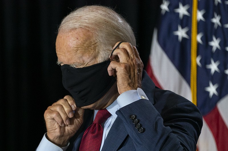 Democratic presidential candidate former Vice President Joe Biden joined by his running mate Sen. Kamala Harris, D-Calif., replaces his face mask after speaking Thursday at the Hotel DuPont in Wilmington, Del.