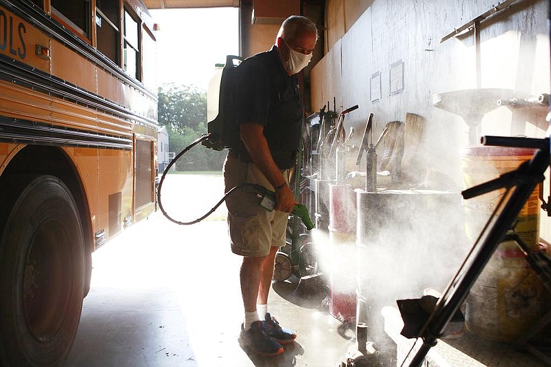 Tim Martin, with Ecovasive, applies the company’s antiviral spray Thursday at the transportation facility for Hope Public Schools. The treatment is one of many extra steps school districts around the state are taking before reopening. (NWA Democrat-Gazette/Dan Holtmeyer) 
