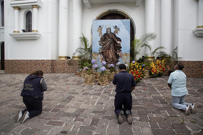 Devotees kneel in prayer Saturday in Guatemala City before a makeshift altar honoring the patron saint of the Guatemalan capital, the Virgin of the Assumption. Catholic pilgrims gathered outside the church that bears her name, despite the pandem- ic-related postponement of religious celebrations marking the occasion. 
(AP/Moises Castillo) 