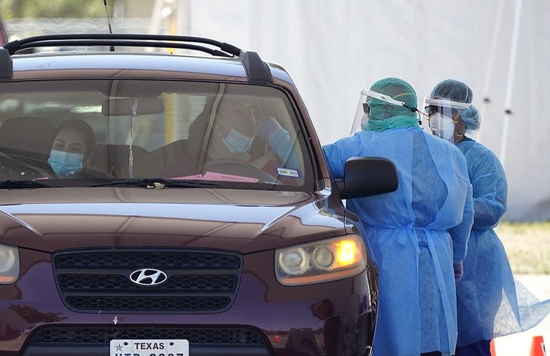 Medical workers test motorists for the coronavirus Friday at a drive-thru site in San Antonio. Coronavirus testing in Texas has dropped signi cantly, mirroring nationwide trends, just as schools reopen and football teams charge ahead with plans to play. More photos at arkansasonline.com/816covid/. 
(AP/Eric Gay) 