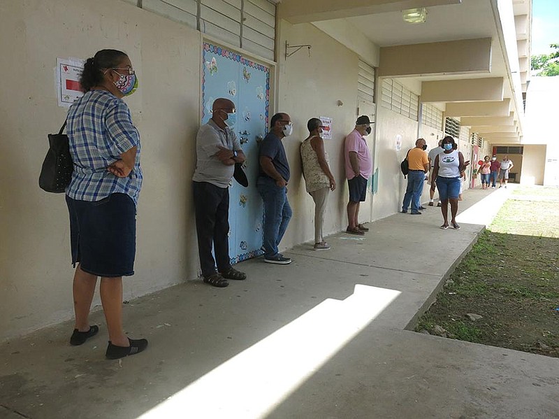 Voters line up to cast their ballots Sunday in Loiza, Puerto Rico. Polling sites in nearly 50 of the is- land’s 78 municipalities opened for a second round of voting after problems with delayed or missing ballots marred the Aug. 9 primary. More photos at arkansasonline.com/817primaries/. (AP/Danica Coto) 