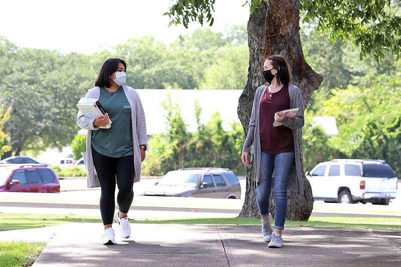 South Arkansas Community College students Amy Lee, left, and Savanna Morgan, both in protective masks, walk on the college’s West Campus on Monday, the first day of the fall semester at SouthArk. (Contributed)