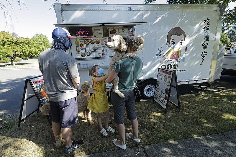 Bobby Price and Catherine Vogt, along with Vogt’s daughter, Avery, 8, wait to order from a food truck  earlier this month near the Seattle suburb of Lynnwood, Wash. More photos at arkansasonline.com/822food/.
(AP/Ted S. Warren)