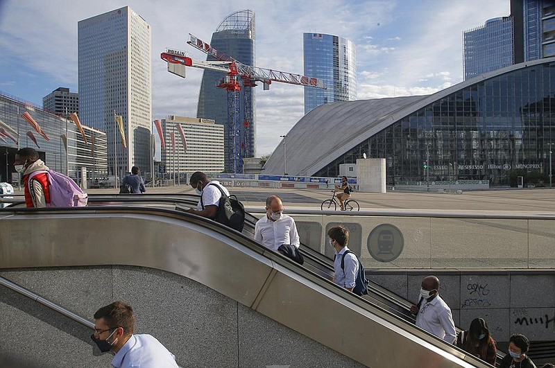 People take an escalator Friday at La Defense business district in Paris. The euro-area economy unexpectedly lost momentum this month as renewed travel restrictions and concerns about the coronavirus took a toll on services.
(AP/Michel Euler)