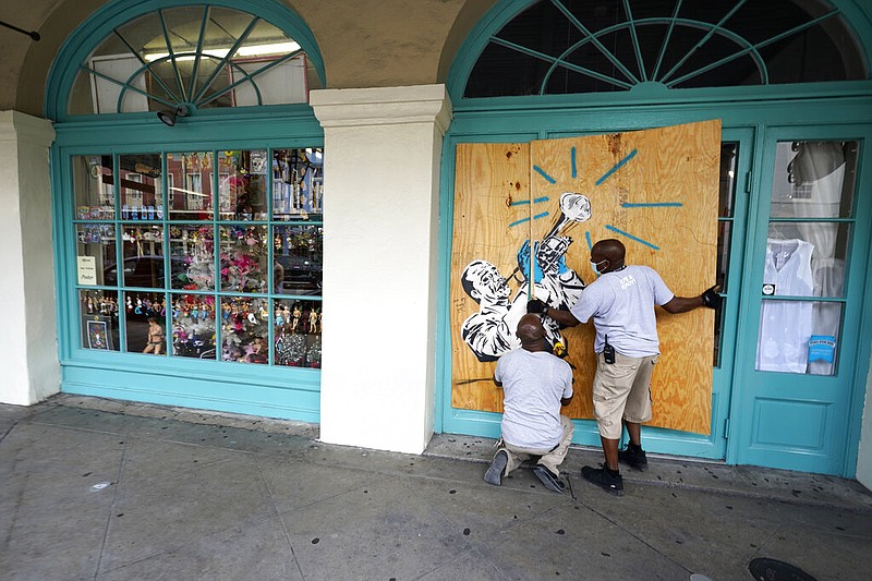 Workers board up shops in the French Quarter of New Orleans on Sunday, Aug. 23, 2020, in advance of Hurricane Marco, expected to make landfall on the Southern Louisiana coast.