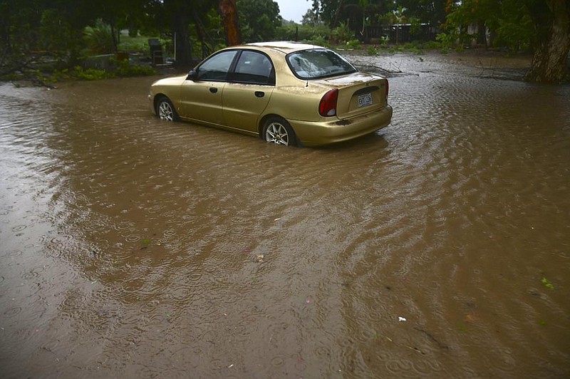 A car sits in floodwaters Saturday caused by Tropical Storm Laura in Salinas, Puerto Rico. (AP/Carlos Giusti) 