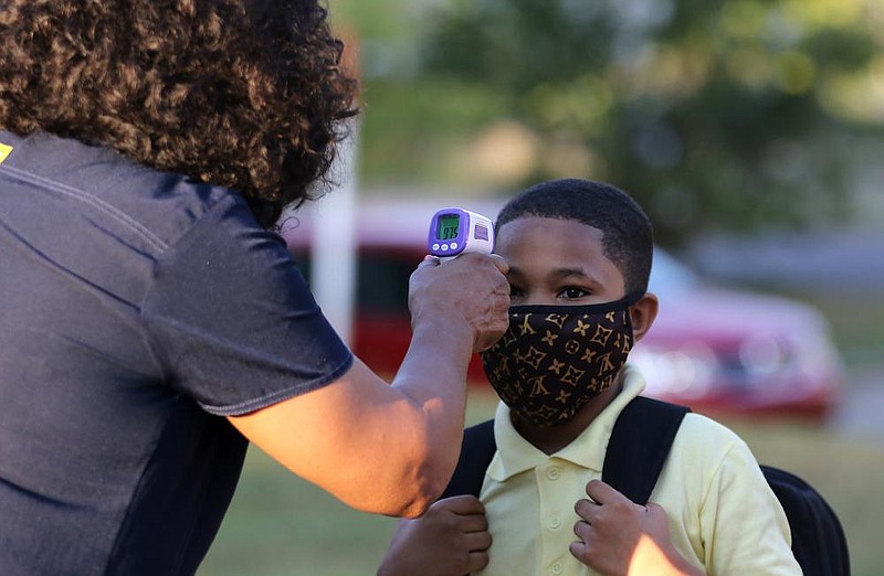 Fifth grader Marcques Haley, 10, gets his temperature checked by school nurse, Rachel White, before entering the building on Monday morning, Aug. 24, 2020, at Stephens Elementary School in Little Rock. (Arkansas Democrat-Gazette/Thomas Metthe)