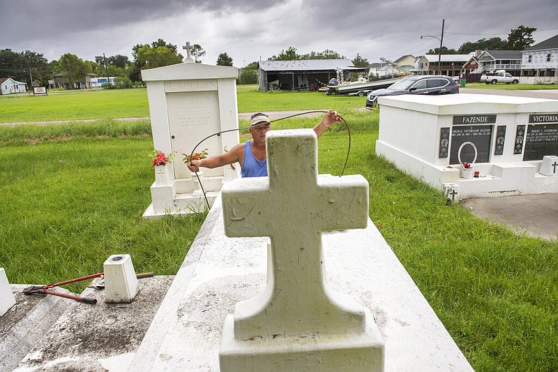Jerry Parria uses steel cable and metal anchors to tie down four tombs belonging to his grandparents and uncles in a small cemetery near Lafitte, La., as residents along the Louisiana coast prepare for two tropical storms, Monday, Aug. 24, 2020. Parria said the tombs floated away during a previous hurricane.