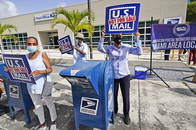 Protesters demonstrate during a "National Day of Action to Save the 'Peoples' Post Office" rally outside Miami's Flagler Station post office on Tuesday, Aug. 25, 2020. The pandemic has pushed the Postal Service into a central role in the 2020 elections, with tens of millions of people expected to vote by mail rather than in-person.