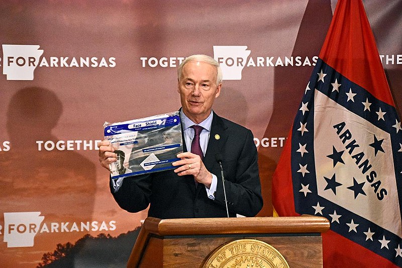 Gov. Asa Hutchinson displays a face shield Wednesday during the coronavirus briefing at the state Capitol. “We have acquired 70,000 of these splash guard face shields, and they are being sent out to every school employee in every district in Arkansas,” Hutchinson said. More photos at arkansasonline.com/827gov/.
(Arkansas Democrat-Gazette/Staci Vandagriff)