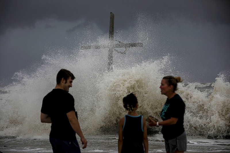 People talk as waves wash ashore and the outer bands of Hurricane Laura bring winds and rain Wednesday, Aug. 26, 2020, in High Island. ( Jon Shapley/Houston Chronicle via AP)

