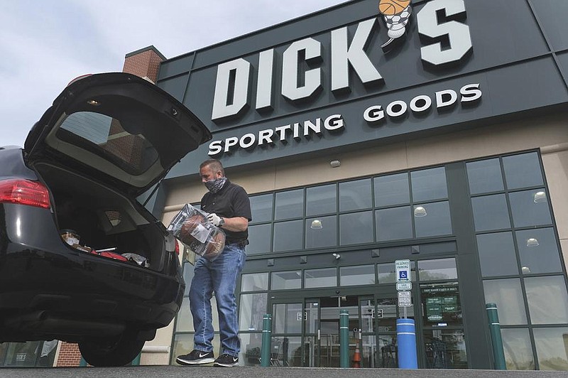 A man places a purchase into a customer’s vehicle outside a Dick’s Sporting Goods store in Paramus, N.J., in May.
(AP)
