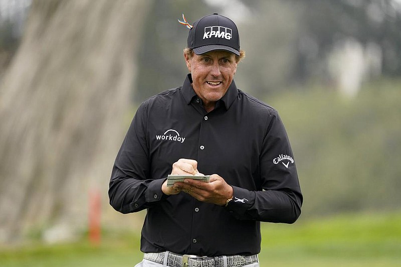 Phil Mickelson looks over a scorecard on the 18th green after his final round of the PGA Championship golf tournament at TPC Harding Park Sunday, Aug. 9, 2020, in San Francisco. (AP Photo/Charlie Riedel)