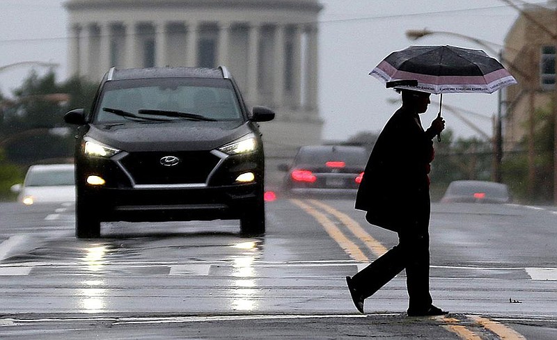 A woman  crosses Capitol Avenue along Broadway as  the  remnants of Hurricane Laura pass through Little Rock on Thursday.
(Arkansas Democrat-Gazette/Thomas Metthe)