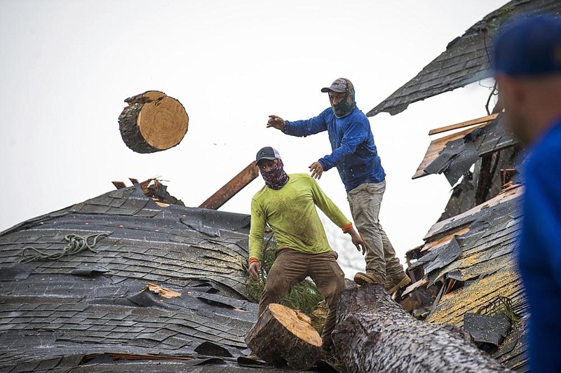 Roofers cut a pine tree into small sections to clear it from atop a house Friday in Lake Charles, La. More photos at arkansasonline.com/829damage/
(AP/The Times-Picayune/The New Orleans Advocate/Chris Granger)