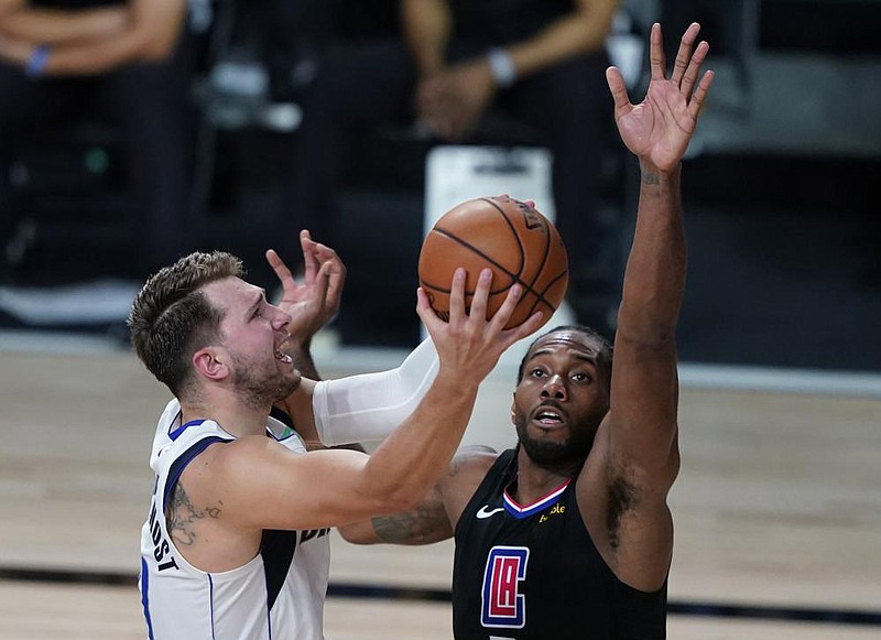 Kawhi Leonard (right) of the Los Angeles Clippers fouls Luka Doncic of the Dallas Mavericks during the second half of Sunday’s first- round playoff game in Lake Buena Vista, Fla. Leonard had 33 points and 14 rebounds to lead the Clippers to a 111-97 victory to win the series. 
(AP/Ashley Landis) 