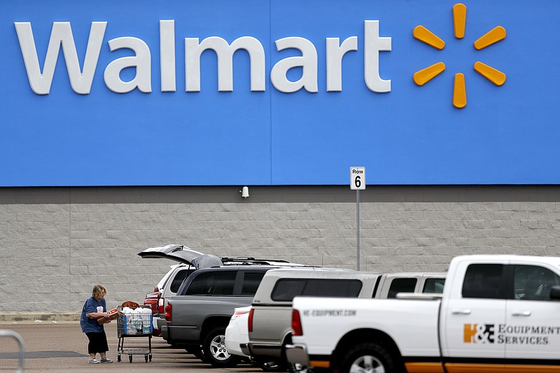 FILE - In this March 31, 2020 file photo, a woman pulls groceries from a cart to her vehicle outside of a Walmart store in Pearl, Miss.
