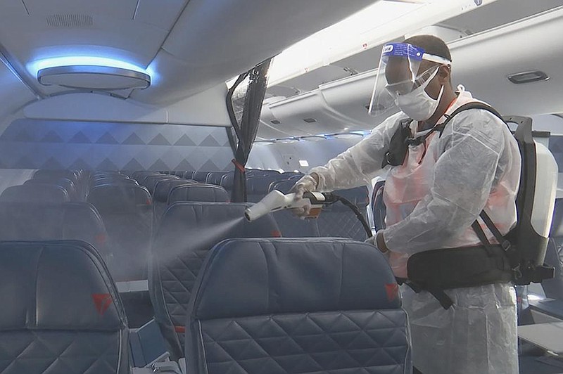 Melaku Gebermariam uses an electrostatic sprayer in July to disinfect the inside of a Delta Air Lines jet parked at Ronald Reagan Washington National Airport in Arlington, Va. (AP/Nathan Ellgren) 