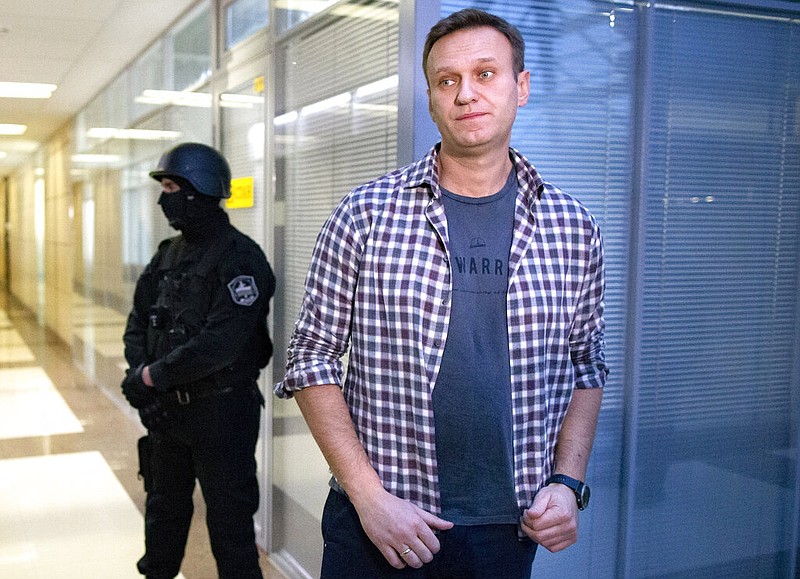 FILE - In this Dec. 26, 2019, file photo, Russian opposition leader Alexei Navalny speaks to the media in front of a security officer standing guard at the Foundation for Fighting Corruption office in Moscow, Russia.
