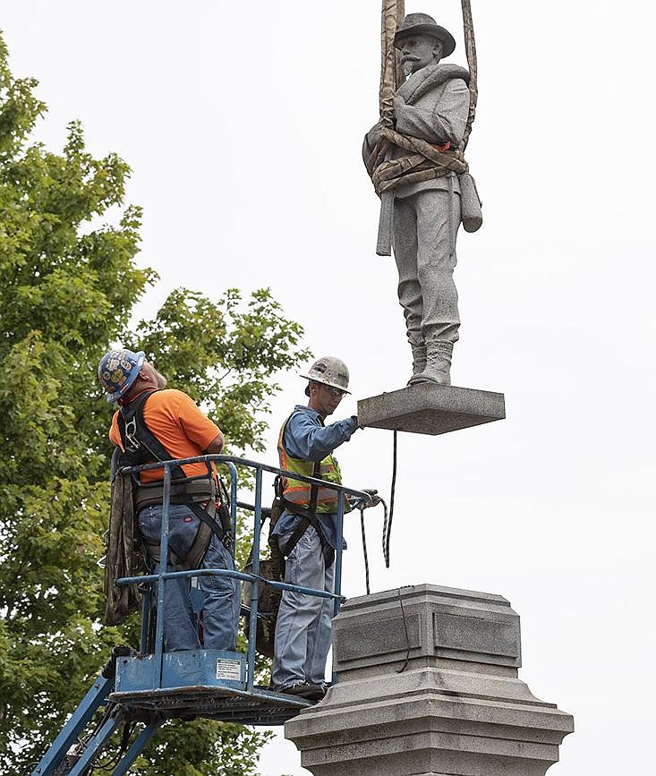 The statue of a Confederate soldier is lifted from its base Wednesday as workers from Nabholz Construction remove it from the Bentonville square. More photos at arkansasonline.com/93removal/.
(NWA Democrat-Gazette/Spencer Tirey)
