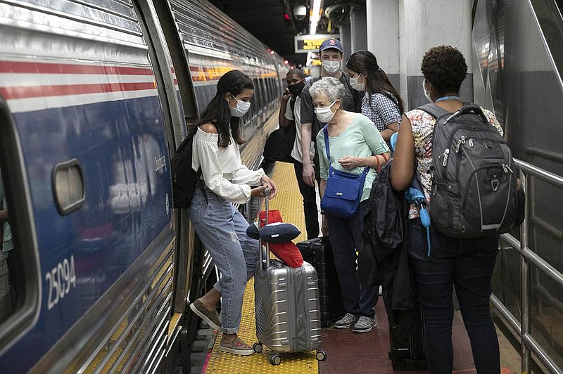 Travelers board a train Aug. 6 at Amtrak’s Penn Station in New York. Amtrak requires passengers  to wear masks in the train stations and while riding the trains.
(AP/Mark Lennihan)