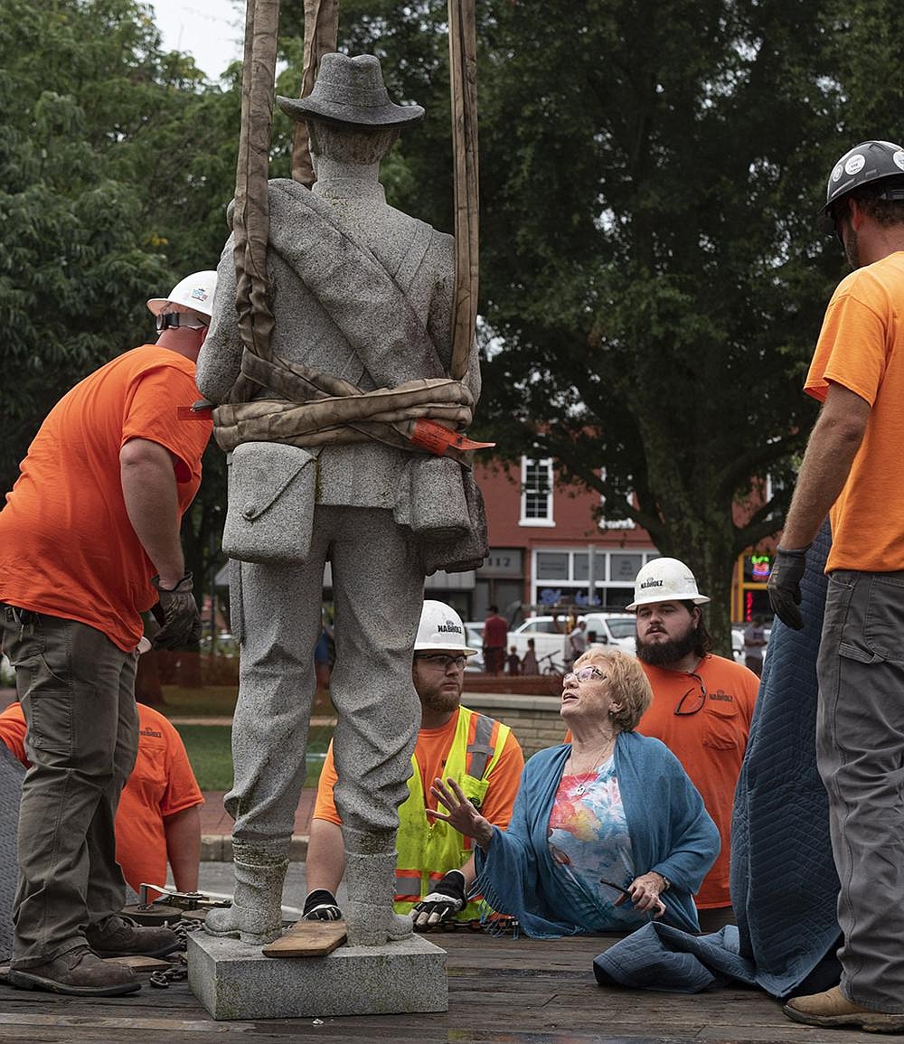 Ann Rossie, with the Arkansas Division of the United Daughters of the Confederacy, checks on the statue of a Confederate soldier after workers from Nabholz Construction removed it from the Bentonville square Wednesday. The Daughters of the Confederacy worked with the Benton County Historical Society and other community members to move the monument to James H. Berry Park, a private park adjacent to the Bentonville Cemetery, where Berry, a former U.S. senator and the 14th governor of Arkansas, is buried.
(NWA Democrat-Gazette/Spencer Tirey)