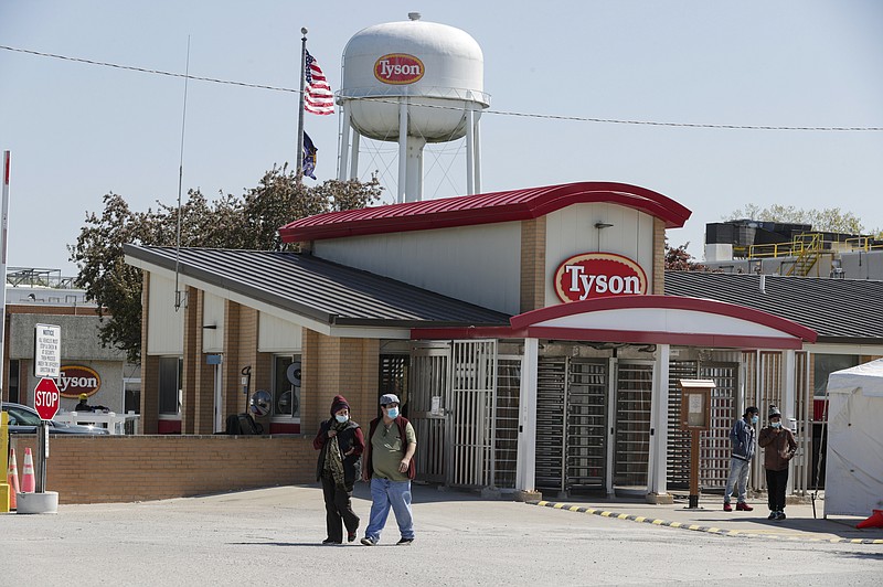 In this May 7 file photo, workers enter and leave the Tyson Foods pork processing plant in Logansport, Ind. Tyson Foods is planning to open medical clinics at several of its U.S. plants to improve the health of workers at the same time it is under pressure to better protect them from the coronavirus.