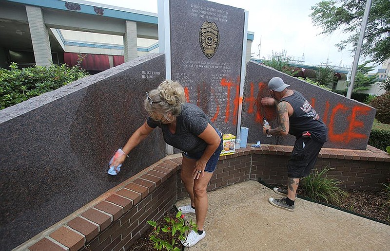 Sherrie Ribaudo and her husband, Tommy, of Maumelle clean graffiti off the fallen police officers’ memorial Thursday outside Little Rock Police Department headquarters after vandals struck overnight. More photos at arkansasonline.com/94graffiti/.
(Arkansas Democrat-Gazette/Thomas Metthe)