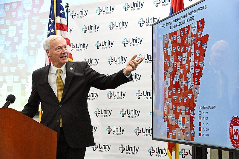 Gov. Asa Hutchinson refers to a map showing the 14-day moving average of coronavirus positivity percentage by county during Friday’s briefing at Unity Health in Searcy. “This is a fairly dramatic exclamation point to end this week and to start the holiday weekend,” Hutchinson said of the increase in cases. More photos at arkansasonline.com/95gov/.
(Arkansas Democrat-Gazette/Staci Vandagriff)
