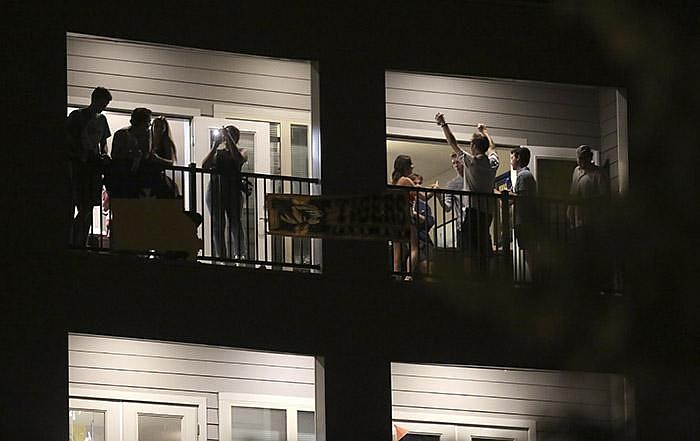 Partiers congregate on the balcony of an apartment in downtown Co- lumbia, Mo., near the University of Missouri campus. As cases spike in college towns, bars have been shut down and students, fraterni- ties and sororities have faced discipline for parties and large events. (AP/Missourian/Dan Shular) 