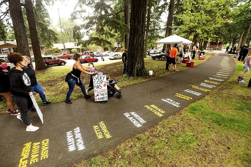 During the 100th consecutive day of demonstrations in Portland, Ore., people Saturday pass by the names of Black people who have died violently. More photos at arkansasonline.com/96portland/. (AP/Noah Berger) 