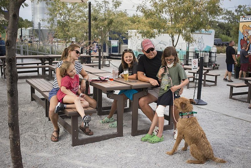 The Price family of Bentonville spends some time outside with their dog Hairy Truman at Bike Rack Brewing in Bentonville. Bike Rack Brewing is relying on its outdoor area including a large patio to attract customers because social distancing has limited indoor seating. (NWA Democrat-Gazette/Charlie Kaijo) 