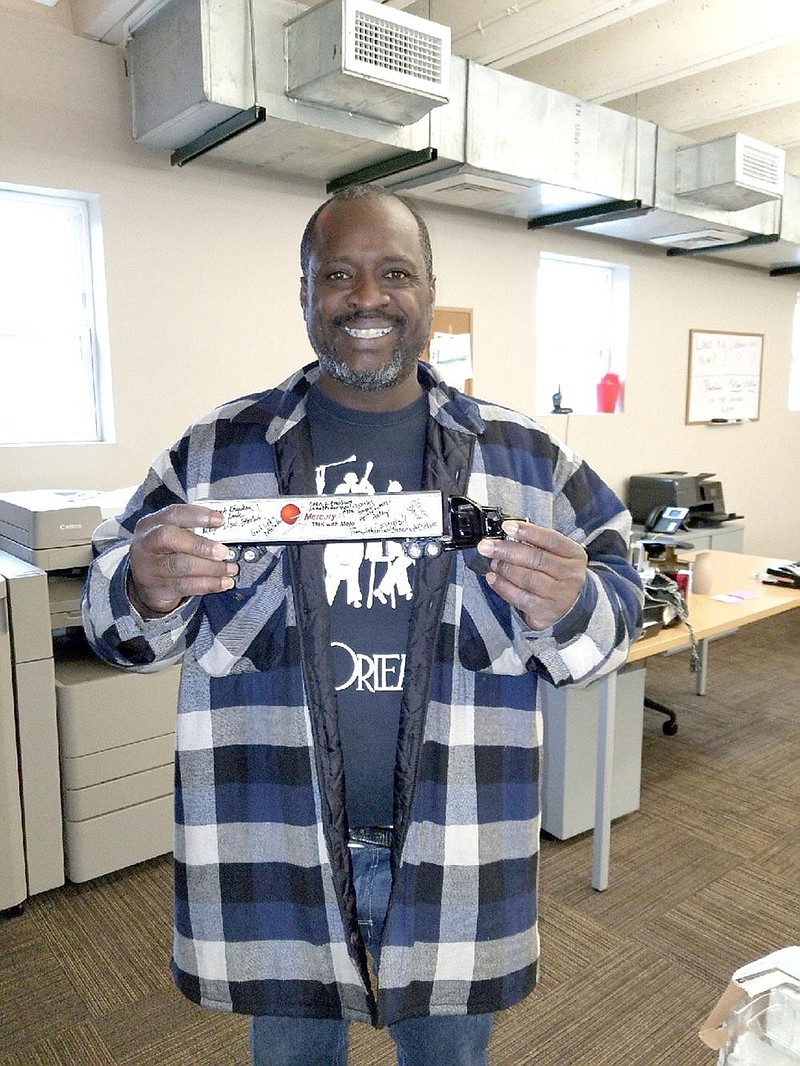Derrick Clark displays a toy truck signed by supporters after earning his commercial driver license via truck driving school. Clark overcame homelessness and addiction, recently founding a schol- arship to help other truck driving students. (Special to the Democrat-Gazette/Kathy Webb) 
