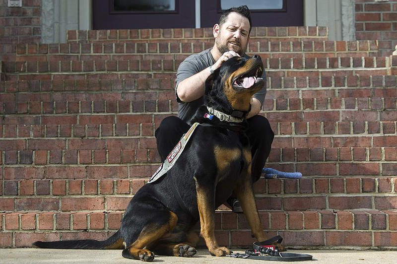 Perry Hopman plays with his service dog, Atlas, outside his home in Benton on Friday. Atlas is trained to help Hopman ward off on- the-job panic attacks, anxiety, and flashbacks from his time as an Army flight medic. (Arkansas Democrat-Gazette/Stephen Swofford) 