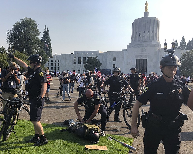 A protester is arrested during a protest at the Oregon State Capitol for a pro-Donald Trump rally at the Capitol in Salem, Ore. on Monday Sept. 7, 2020. (AP Photo/Andrew Selsky)