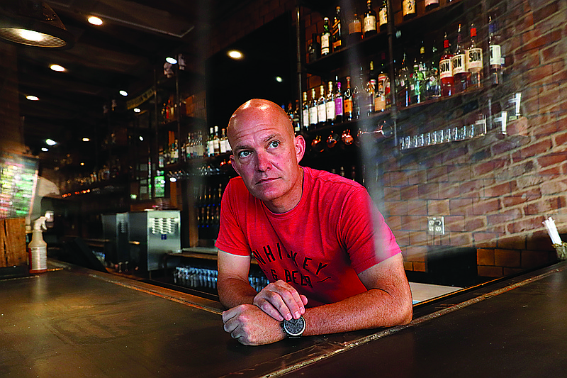 Jeff Brightwell, owner of Dot's Hop House, is framed between protective shielding placed over the bar as he poses for a photo at his establishment in the Deep Ellum entertainment district in Dallas, Thursday, Aug. 20, 2020. story.lead_photo.caption